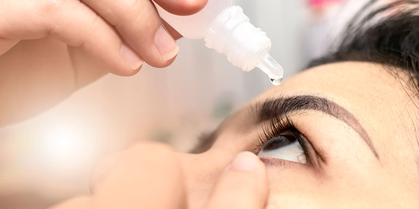 woman putting eye drops in her eyes in eye clinic in Abuja